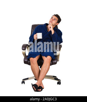 Full length portrait of confident young man, wears blue bathrobe, seated relaxed in his armchair in the morning drinking a cup of coffee isolated over Stock Photo