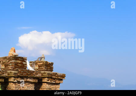 Old ruined Grit stone stone wall background against blue sky with cotton wool clouds and Kanchenjunga mountain range. Rabdentse Ruins, West Sikkim, In Stock Photo