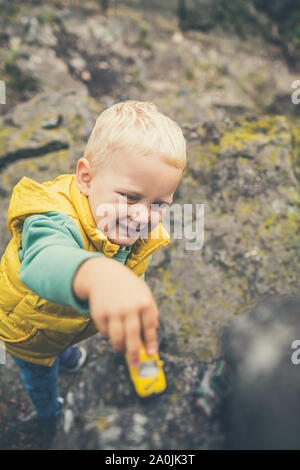 Toddler boy playing with toys on a rock. Little child walking on rocky mountains. Stock Photo