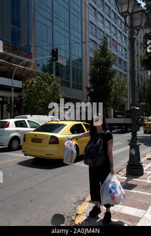 woman holding shopping bags hailing taxi stadiou athens attica greece Stock Photo