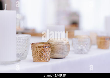 A variety of candlesticks and candles on the white table. Minimalist decor of modern wedding Stock Photo