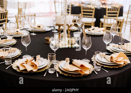 A black tablecloth, expensive utensils and gold details decorate the  wedding table Stock Photo - Alamy