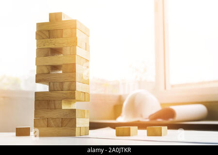 the blocks wood tower game with architectural engineer plans or blue prints compasses ,pencils and ruler on wooden table, plan and building concept. Stock Photo