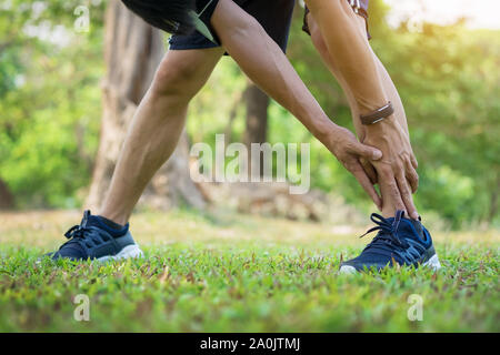 Male runner training in cold winter doing warm-up leg stretching exercise Stock Photo