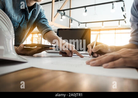 Two Architects engineer discussing  data working and tablet, laptop with blueprint - Closeup on hands and project print. Stock Photo