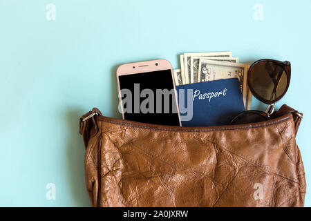 Vintage woman bag with contents for travelling. Passport, smartphone and sunglasses inside the woman bag.Travel concept. Stock Photo