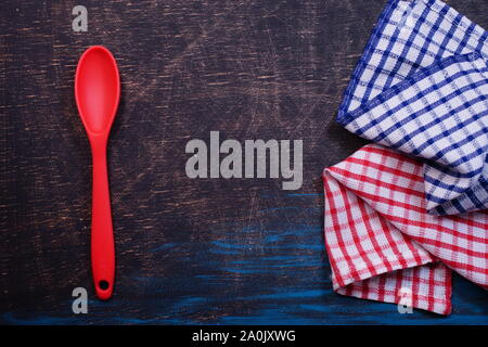Red plastic kitchen spoon on a black table with a red checkered towel Stock Photo