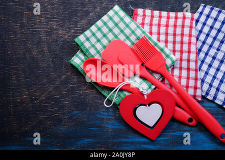 Red plastic kitchen utensils on a black table with checkered towels Stock Photo