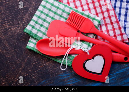 Red plastic kitchen utensils on a black table with checkered towels Stock Photo