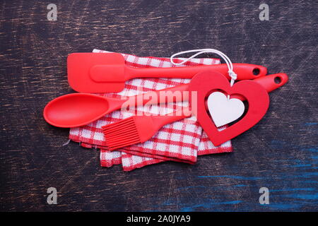 Red plastic kitchen utensils on a black table with checkered towels Stock Photo