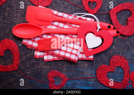 Red plastic kitchen utensils on a black table with checkered towels Stock Photo