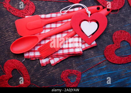 Red plastic kitchen utensils on a black table with checkered towels Stock Photo