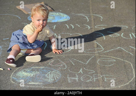 Glasgow, UK. 20 September 2019.  PICTURED: An infant stands above a globe with a slogan which reads 'GIVE US HOPE'. Will there be anything left for our future generations? Scenes from a planned protest in George Square this afternoon after strikes started a year ago by 16-year-old Swedish schoolgirl named Greta Thunberg. Hundreds of chalk marked slogans littered the concrete of George Square with protestors from all ages and backgrounds. Credit: Colin Fisher/Alamy Live News Stock Photo