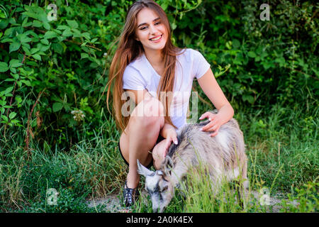 Protect animals. Veterinarian occupation. Treating animals at farm. Woman play cute goat. United with nature. Animals law. Girl and goat green grass. Farm and farming concept. Village animals. Stock Photo