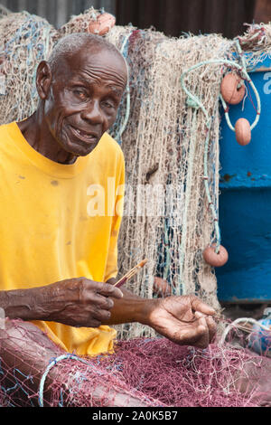 Senior aged balding man is repairing his fishing net, Scotts Head, Dominica, West French Indies, Caribbean, Central America Stock Photo