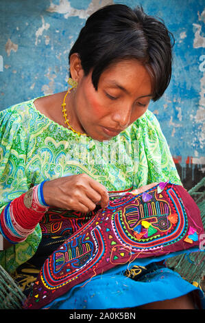 Kuna Indian woman wearing a traditional mola blouse, sews and embroiders a handcrafted mola, Kuna (Guna)Yala/San Blas Islands, Caribbean coast, Panama Stock Photo