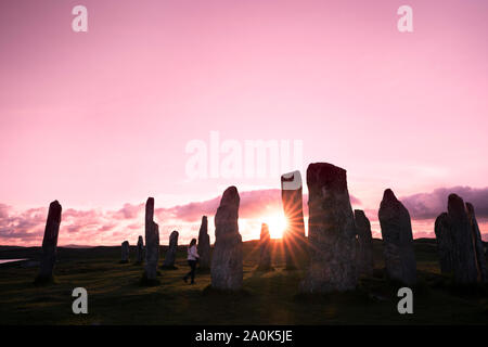 Starburst sun setting at the Callanish Standing Stones silhouetted against a pastel sky on the Isle of Lewis, Outer Hebrides, Scotland, UK, Europe Stock Photo