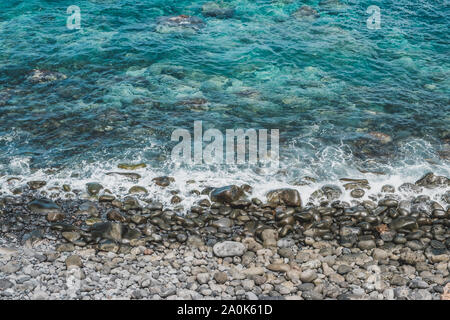 ocean waves on stone beach with black pebbles - Stock Photo