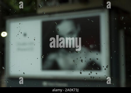 Blurred image of billboard with woman portrait and raindrops on glass Stock Photo