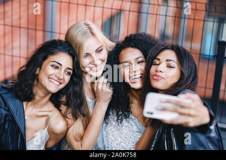 Group of happy female friends making photographs on smartphone outdoors Stock Photo