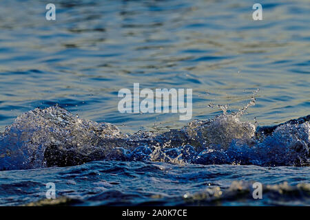 A close up image of some ocean waves rippling into the shore creating some splashing and bubbles on Vancouver Island British Columbia Canada. Stock Photo