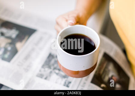 Cropped image of woman holding coffee while reading newspaper Stock Photo