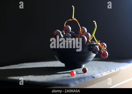 Fresh black grapes in a black cup isolated on dark background Stock Photo