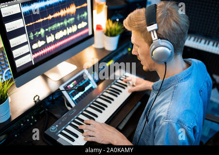 Contemporary musician in headphones recording new music and songs in studio Stock Photo