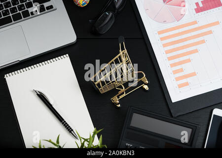 Gold cart, cash and gadgets on a black table. Stock Photo