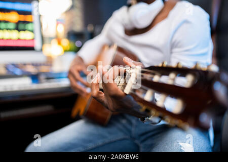 Hands of young musician of African ethnicity on strings of acoustic guitar Stock Photo