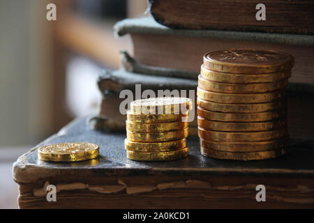 Money growth idea. Stacks of gold coins and vintage books. Stock Photo