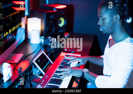 Young serious African-american man making new music while sitting in studio Stock Photo