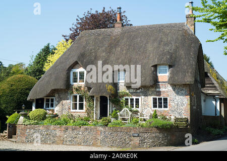 Typical English stone built thatched cottage brick and flint construction, roof thatching, chimneys in Ramsbury, Wiltshire, UK Stock Photo