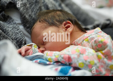 Newborn Baby Girl Sleeping in Mother's Arms in Hospital Stock Photo