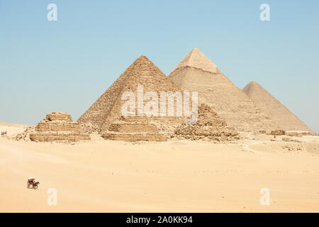 Horse drawn carts near Giza pyramids. Khufu, Khafre, Menkaure and pyramids Queens are seen from desert. Stock Photo