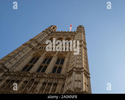 LONDON, UK - SEPTEMBER 20 2019: Union Jack flag flying over the looming Houses of Parliament against a blue sky, Westminster, London Stock Photo