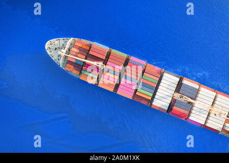 Large full loaded container ship sailing bright blue sea. Top aerial view Stock Photo