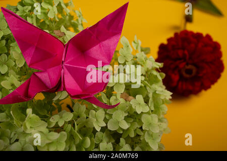 origami butterfly on a green bush in a basket on a colored background beautiful bouquet studio close shot handmade crafted art Stock Photo