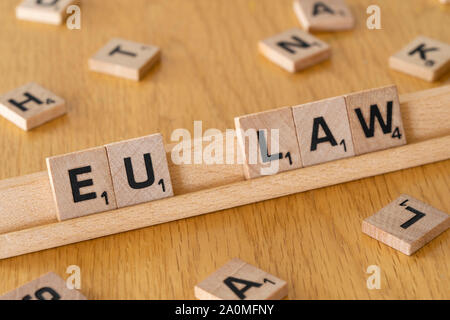 Wooden scrabble letters on a rack spelling out the words EU Law Stock Photo