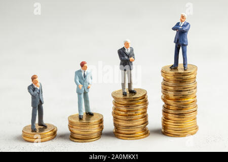 Successful businessman with big profits at the top of the stairs by coins and less successful businessmen with small companies. Adequate investment in the company Stock Photo