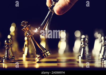 Closeup king chess piece defeated enemy or trade competitor by checkmate at end of chessboard game. Businessman moving chess to success competition by Stock Photo