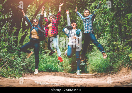 Group of happy Asian teenage adventure traveler trekkers group jumping together in mountain at outdoor forest background. Young hiker friends supporti Stock Photo