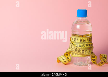 Plastic bottle with water and measuring tape on pink background. Copy space for text Stock Photo
