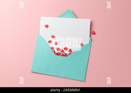 Love letter with red hearts. Blank template with place for text on postcard. Green envelope on pink background. mock-up. Stock Photo