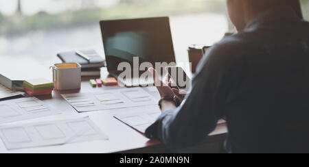 Team of young professional UI graphic designer discussing on their smartphones templates together Stock Photo