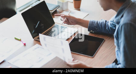 Close-up view of UX web developer working on his project about UX template while using laptop computer and tablet Stock Photo