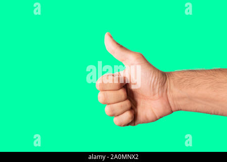 Thumbs up hand sign isolated on a green background. Stock Photo
