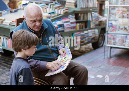 Buenos Aires, Argentina - March 24 2012: Streets of San Telmo a neighborhood of Buenos Aires city. A neighbor teaches his grandson to read on the stre