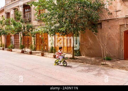 Kashgar Renovated Old City Uyghur Girl is Driving a Bicycle down the Street on a Sunny Blue Sky Day Stock Photo