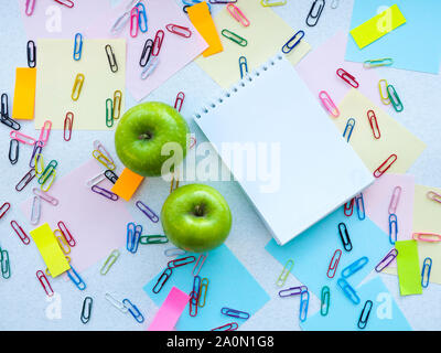 Apple, Notepad, paper clips, stickers on the table Stock Photo
